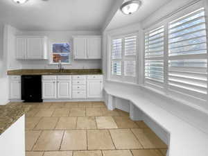 Kitchen featuring dishwasher, white cabinets, and a sink