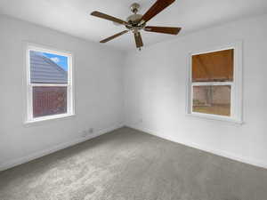 Empty room featuring carpet flooring, a ceiling fan, and baseboards