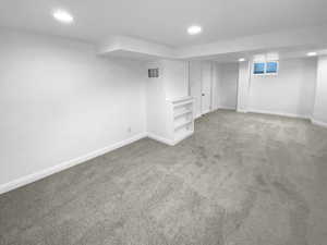 Finished below grade area with recessed lighting, carpet, visible vents, and baseboards