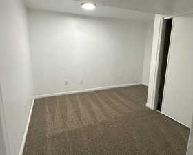 Unfurnished room with baseboards and dark carpet