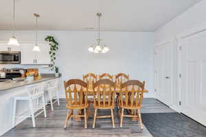 Dining room featuring dark wood-style floors, baseboards, visible vents, and an inviting chandelier