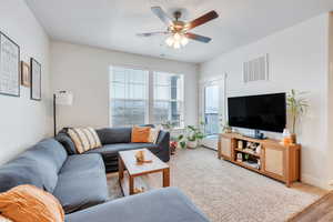 Living area with baseboards, a textured ceiling, visible vents, and a ceiling fan