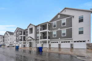 Exterior space featuring a residential view, stone siding, driveway, and an attached garage