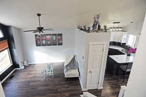 Interior space with dark wood-type flooring, vaulted ceiling, baseboards, and a ceiling fan