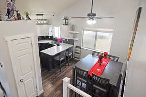 Dining area with a ceiling fan, vaulted ceiling, and dark wood-style flooring