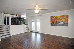 Spare room featuring ornamental molding, french doors, dark wood finished floors, and a textured ceiling