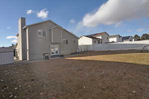 Rear view of property featuring french doors, fence, a chimney, and a lawn