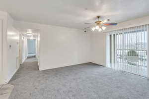 Spare room featuring light carpet, baseboards, and a ceiling fan