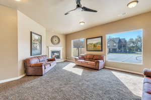 Living area featuring ceiling fan, carpet floors, visible vents, baseboards, and a tiled fireplace