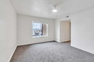 Unfurnished room featuring carpet, visible vents, ceiling fan, and baseboards