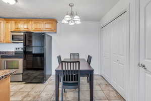 Dining area with light tile patterned flooring, baseboards, and an inviting chandelier