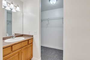 Bathroom with a spacious closet, vanity, and baseboards