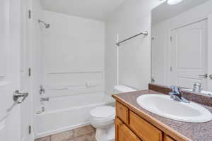 Full bath with shower / tub combination, vanity, toilet, and tile patterned floors