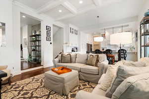 Living area with beam ceiling, dark wood finished floors, recessed lighting, ornamental molding, and coffered ceiling