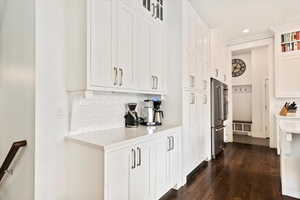 Kitchen featuring tasteful backsplash, white cabinets, high quality fridge, glass insert cabinets, and light countertops