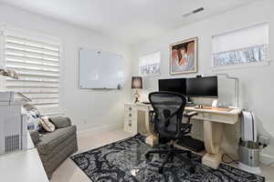 Office space / bedroom featuring light carpet and baseboards