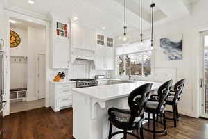 Kitchen featuring glass insert cabinets, white cabinetry, and a peninsula