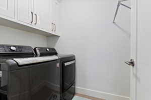 Laundry area featuring baseboards, cabinet space, and washing machine and clothes dryer