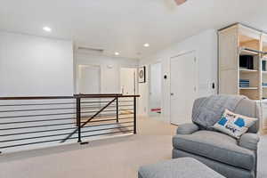 Sitting room with recessed lighting, baseboards, light carpet, and an upstairs landing