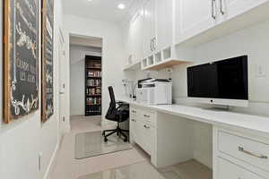 Home office with light colored carpet and built in study area