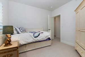 Bedroom featuring light carpet and baseboards