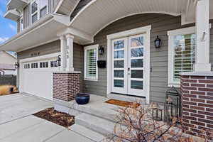 Entrance to property with a garage, concrete driveway, and brick siding