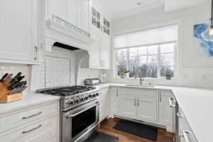 Kitchen with light countertops, high end stainless steel range, glass insert cabinets, and pendant lighting