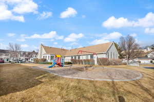 Back of property with a playground and a lawn