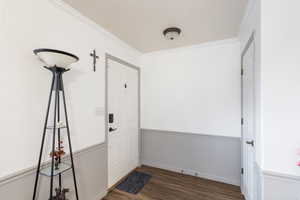 Foyer entrance featuring crown molding and dark hardwood / wood-style floors