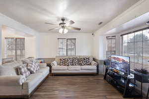 Living room with ceiling fan, ornamental molding, dark hardwood / wood-style floors, and a textured ceiling