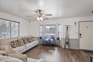 Living room with crown molding, ceiling fan, dark hardwood / wood-style floors, and a textured ceiling