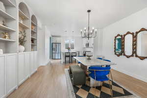Dining space featuring light wood-style floors, a notable chandelier, and baseboards