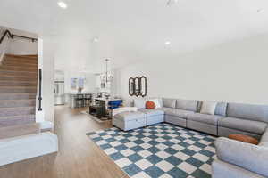 Living room with light wood-style flooring, stairs, a notable chandelier, and recessed lighting