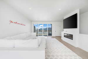 Living area with recessed lighting, baseboards, wood finished floors, and a glass covered fireplace