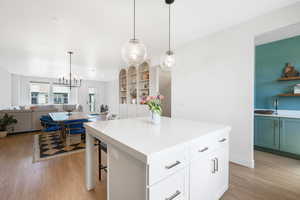 Kitchen with a kitchen island, white cabinetry, open floor plan, and light countertops