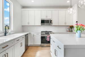 Kitchen featuring light countertops, appliances with stainless steel finishes, a sink, and white cabinets