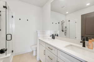 Full bathroom with toilet, double vanity, a sink, and recessed lighting