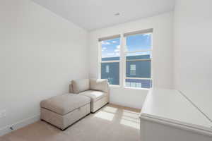 Living area with baseboards, visible vents, and light colored carpet