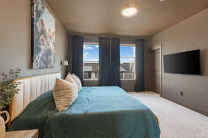 Carpeted bedroom featuring a textured ceiling and baseboards