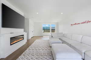 Living area featuring recessed lighting, visible vents, dark wood-style flooring, and a glass covered fireplace