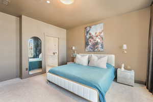 Carpeted bedroom featuring baseboards, visible vents, and ensuite bathroom