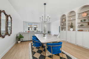 Dining room featuring light wood-type flooring, an inviting chandelier, and baseboards