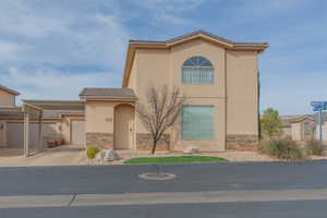 View of front of property featuring stone siding, concrete driveway, a tiled roof, and stucco siding