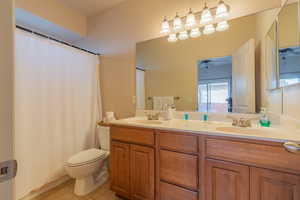 Full bathroom with double vanity, tile patterned flooring, toilet, and a sink