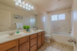 Full bathroom with shower / tub combo with curtain, tile patterned flooring, a sink, and double vanity