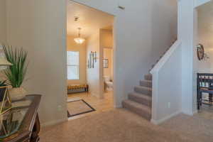 Entrance foyer featuring light tile patterned floors, visible vents, stairway, light carpet, and baseboards