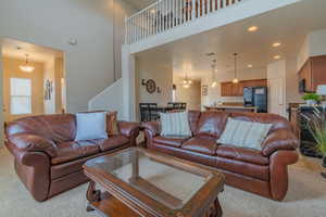 Living room featuring a towering ceiling, visible vents, light colored carpet, and recessed lighting