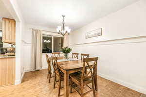 Dining space with light wood-type flooring, an inviting chandelier, and baseboards