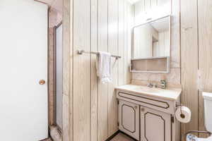 Bathroom featuring wood walls, vanity, and toilet