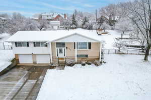 Split foyer home with a garage, brick siding, and driveway